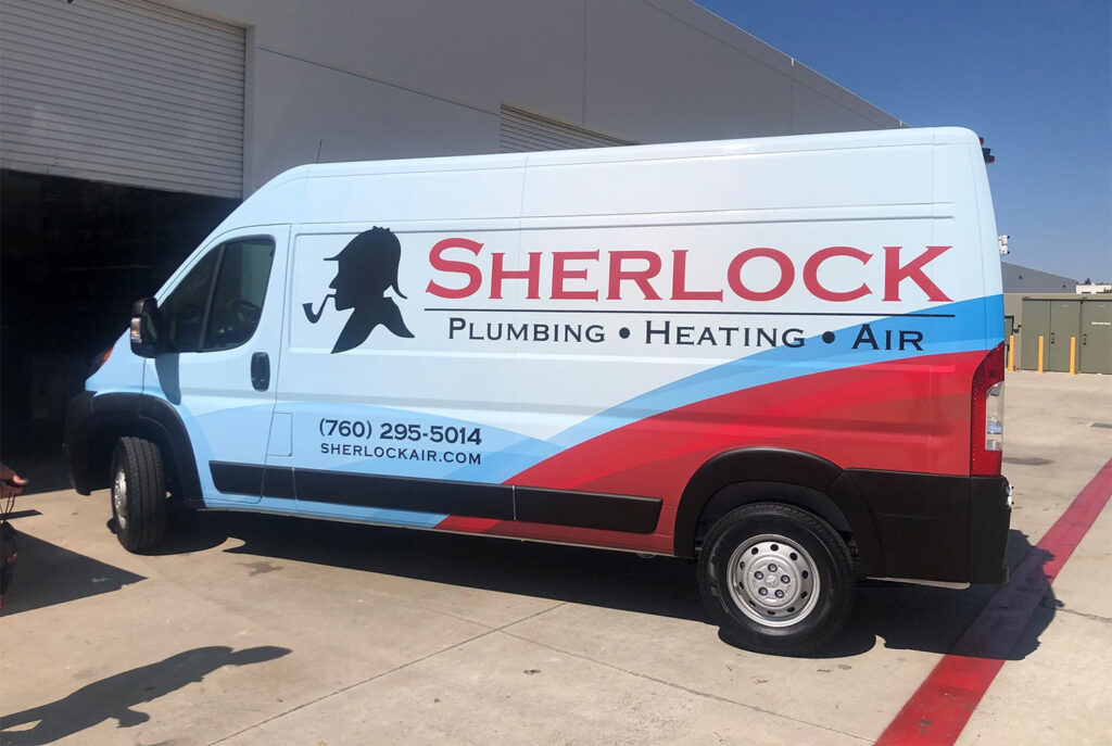 A light blue van with "Sherlock Plumbing Heating Air" and a Sherlock Holmes silhouette logo on the side, parked outside a building. The van displays a phone number and website.