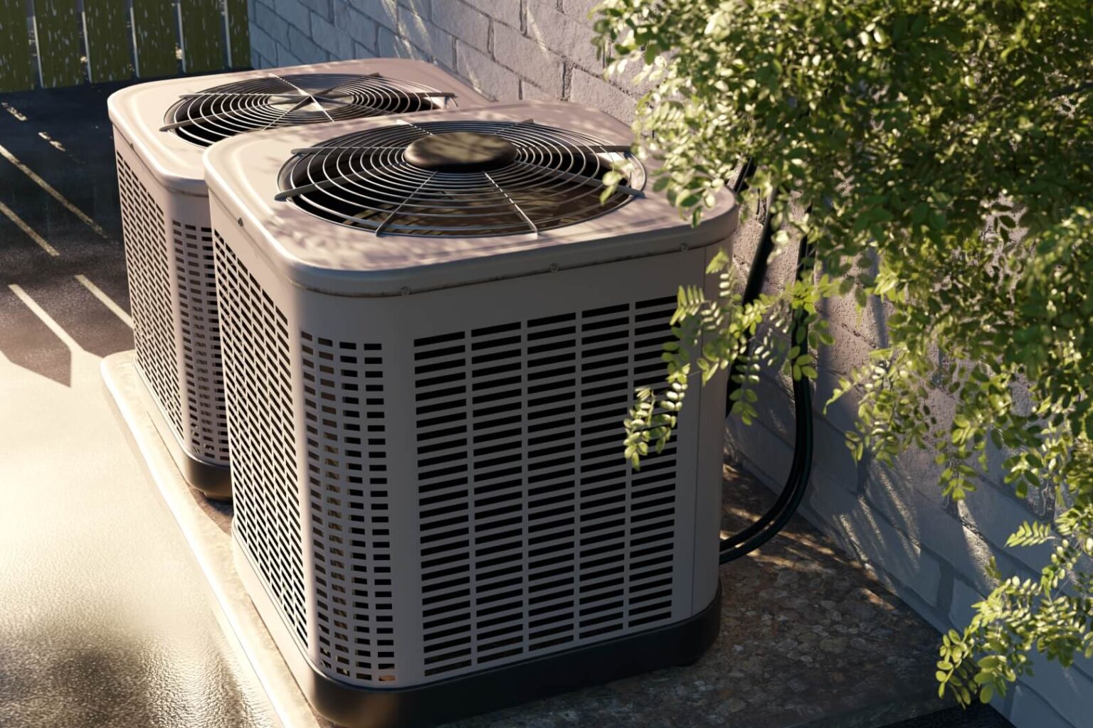 Two outdoor air conditioning units sit on a concrete pad next to a brick wall. Sunlight filters through nearby foliage, casting shadows—an inviting scene for anyone needing Heat Pump Repair San Diego services.